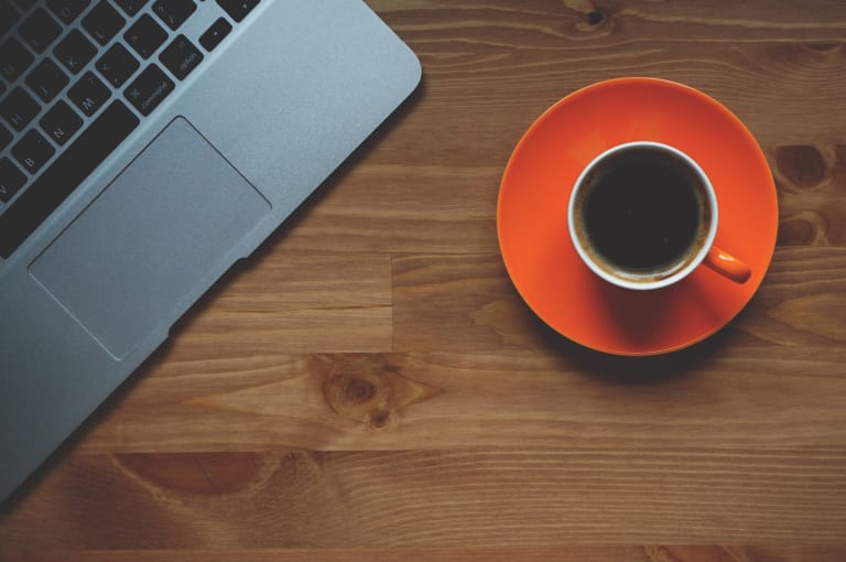 Tasse de café sur un bureau à côté d'un ordinateur