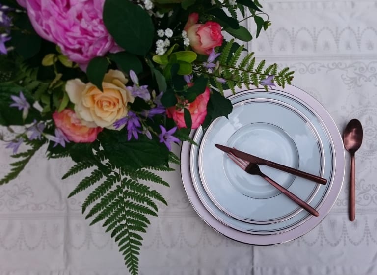 Assiette avec des couverts posée à côté de fleurs
