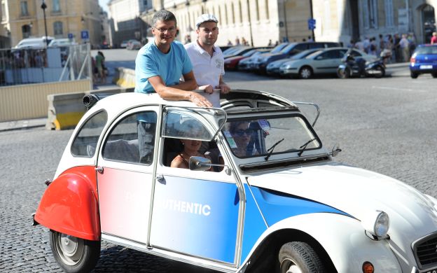 Adventures in Montmartre: Tourists strike a pose with a classic 2CV, immersing in Parisian charm and joie de vivre.