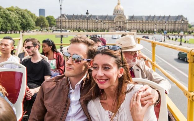 Joyful couple capturing the serenity of Paris on a Tootbus, savoring the tranquil empty streets, creating memories with a picture-perfect pose.