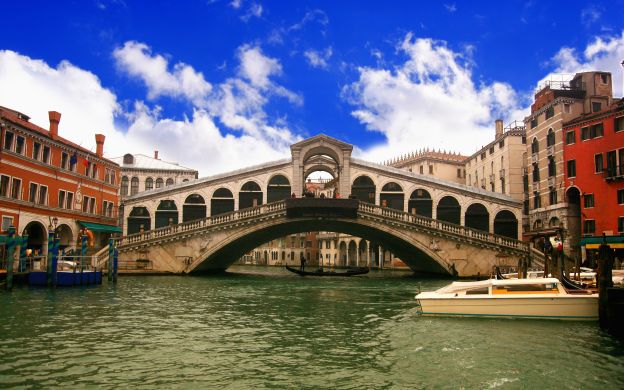 A stunning photo captures the beauty of Venice's canals and Rialto Bridge, epitomizing the city's historic charm and allure.