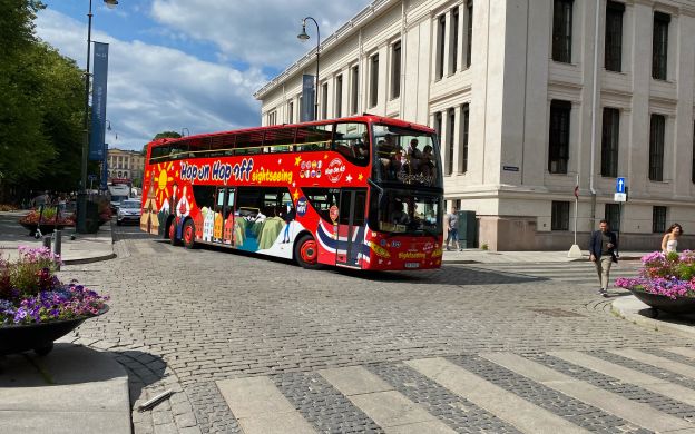 Vibrant red Hop-On, Hop-Off Sightseeing bus exploring the streets of Oslo, showcasing the city's iconic landmarks and attractions.