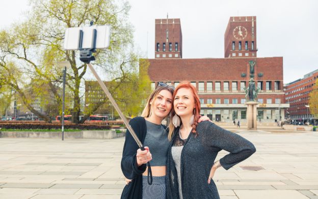 Tourists cherishing the moment, capturing perfect selfies in Oslo using a selfie stick, creating lasting memories of their visit.