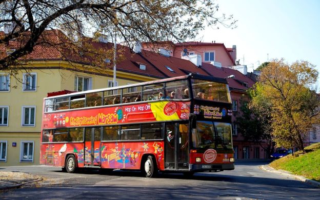 Dynamic City Sightseeing Warsaw: Hop-On, Hop-Off bus bustling through Warsaw, brimming with enthusiastic passengers on a captivating city tour.