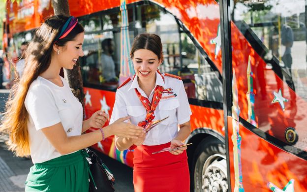 A friendly bus hostess with a smiling face welcoming passengers to embark on the City Sightseeing Hop-On, Hop-Off bus and explore Benalmadena.