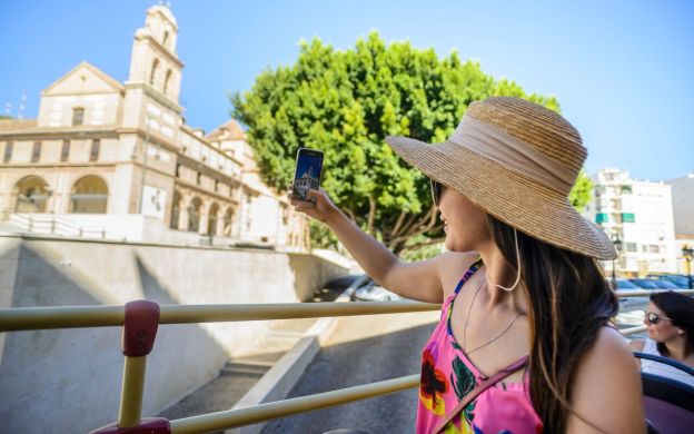 Young traveler capturing the beauty of Carmen Thyssen Museum in Malaga from a comfortable seat on the Hop-On Hop-Off bus.