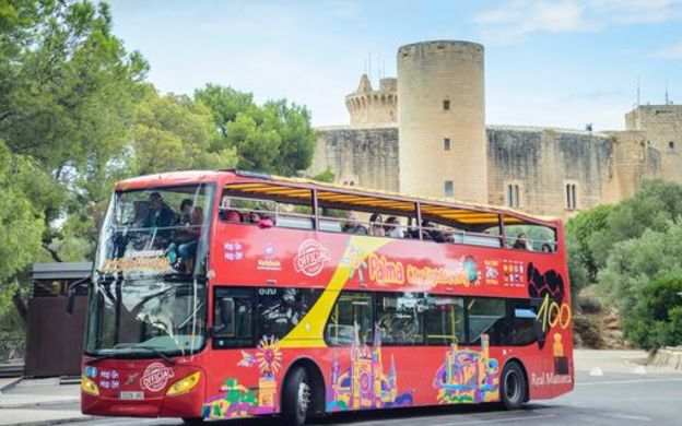 Dynamic red City Sightseeing Hop-on Hop-off bus touring Mallorca, offering passengers stunning sights and panoramic views of the island.