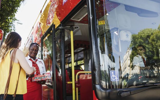 Friendly bus hosts warmly greeting passengers aboard the City Sightseeing Seville Hop-On Hop-Off bus, creating a welcoming atmosphere.