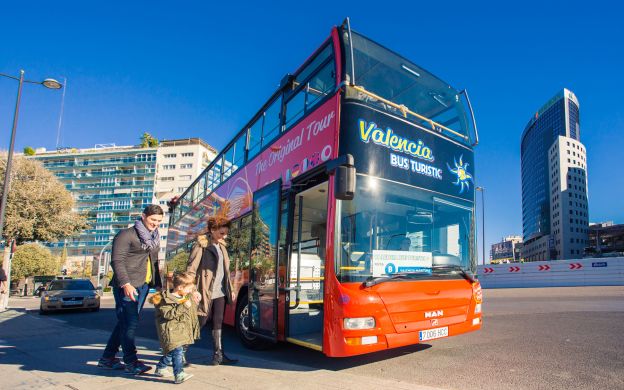 A joyful family embarking on the Valencia Turistic Hop-On, Hop-Off bus, ready for an exciting city exploration together.
