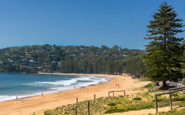 Captivating aerial view of Sydney Beach: golden sands meet azure waves, cityscape blends with coastline, nature and urbanity entwined.