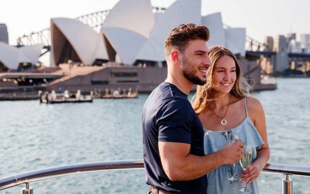 Adorable couple strikes a pose on the cruise ship's deck, framed by the iconic harbor cruise, capturing love against beauty.