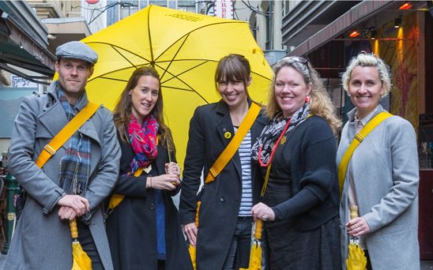 Tourists capturing memories in Melbourne city lanes, striking poses for a photo to cherish the vibrant urban atmosphere.