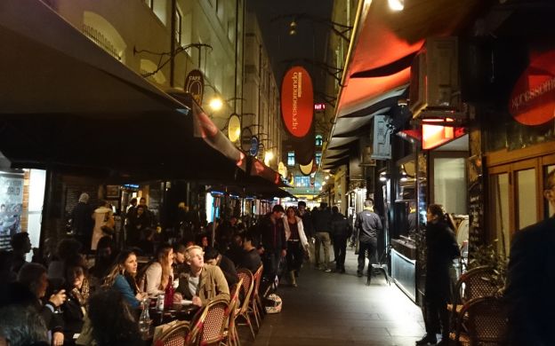 Melbourne's bustling street café, alive with diners relishing delicious food and drinks, captures the city's vibrant culinary scene.