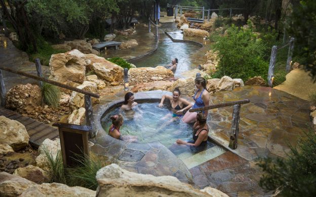 Tourists relax at the Peninsula Hot Springs, enjoying the serene atmosphere and indulging in a blissful experience.