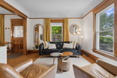 Living room with a black leather couch, yellow curtains, and wooden accents.
