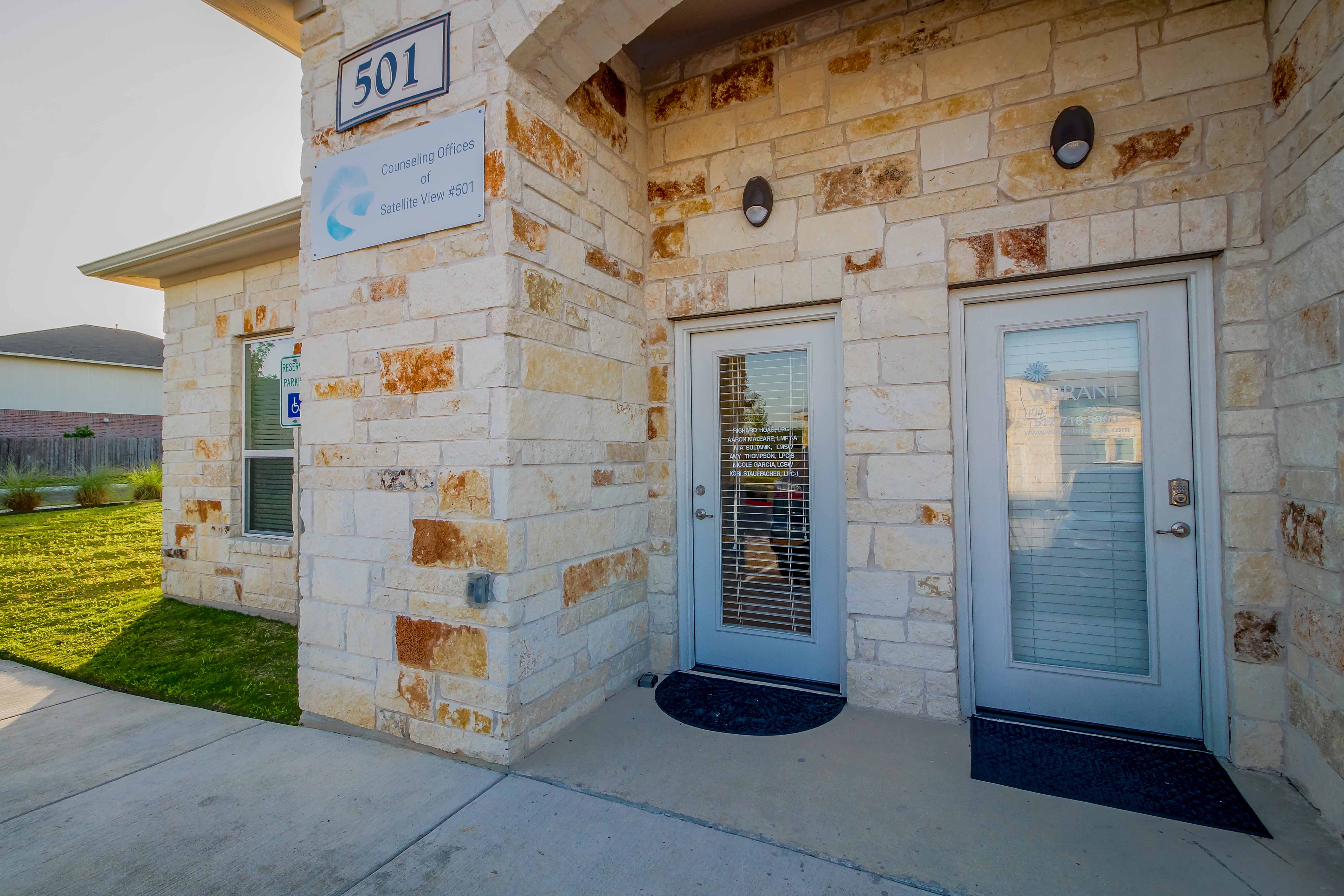 A therapy room at the Austin office with a grey couch and stone wall