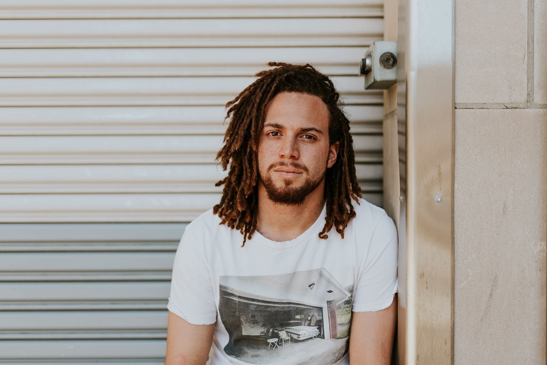 A young man sitting on a concrete ledge against an open blue sky