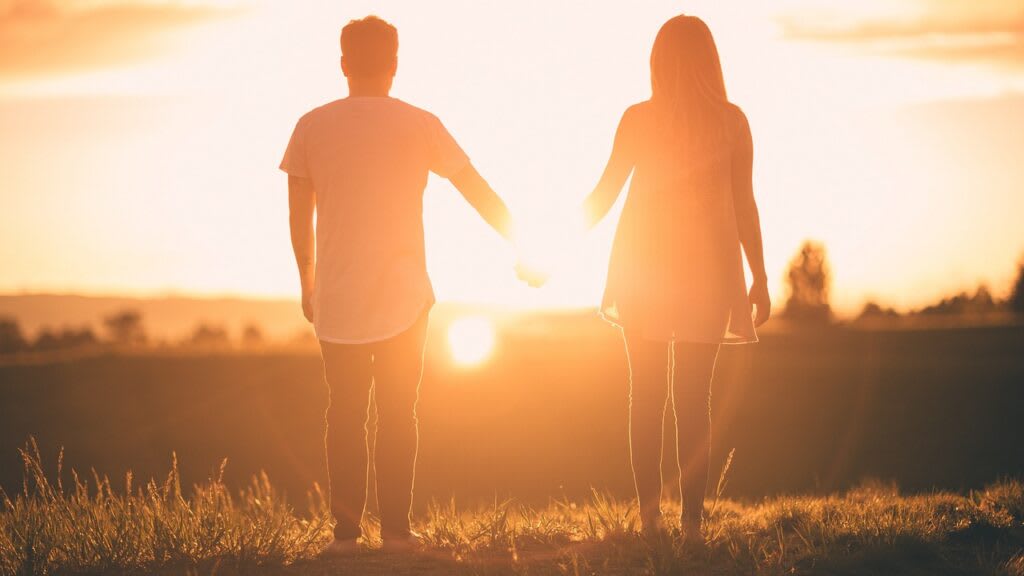 A couple holding hands at sunset in golden light