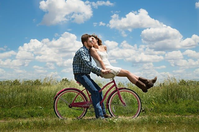 A joyful couple on a bicycle under a blue sky