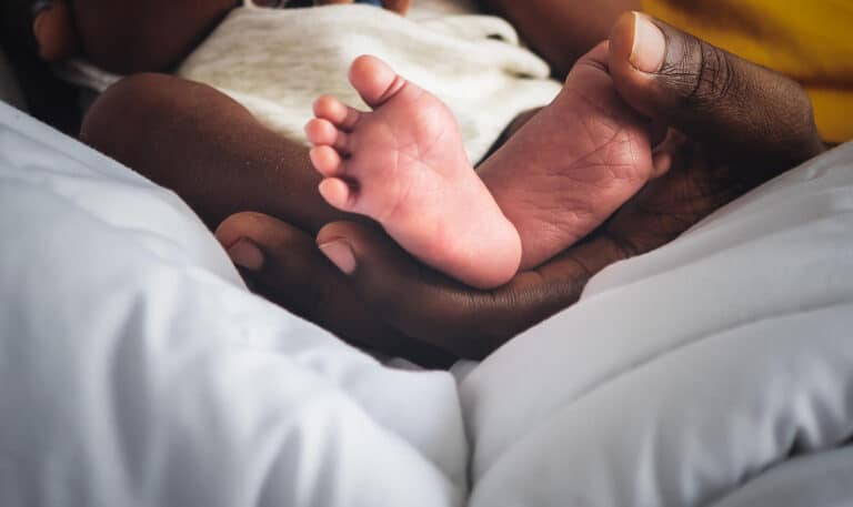 A parent's hand holding a newborn's feet