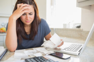 A person looking overwhelmed while going over bills and a budget