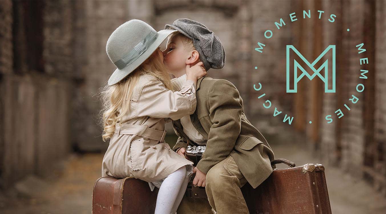 Kids sitting on suitcases and kissing. Text: Moments, Memories, Magic, MINNēSTAY Logo.