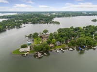 A scenic aerial view of a lakeside community featuring homes, green trees, and boats on the water.