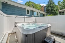 Hot tub in a backyard setting with a fence and blue sky.