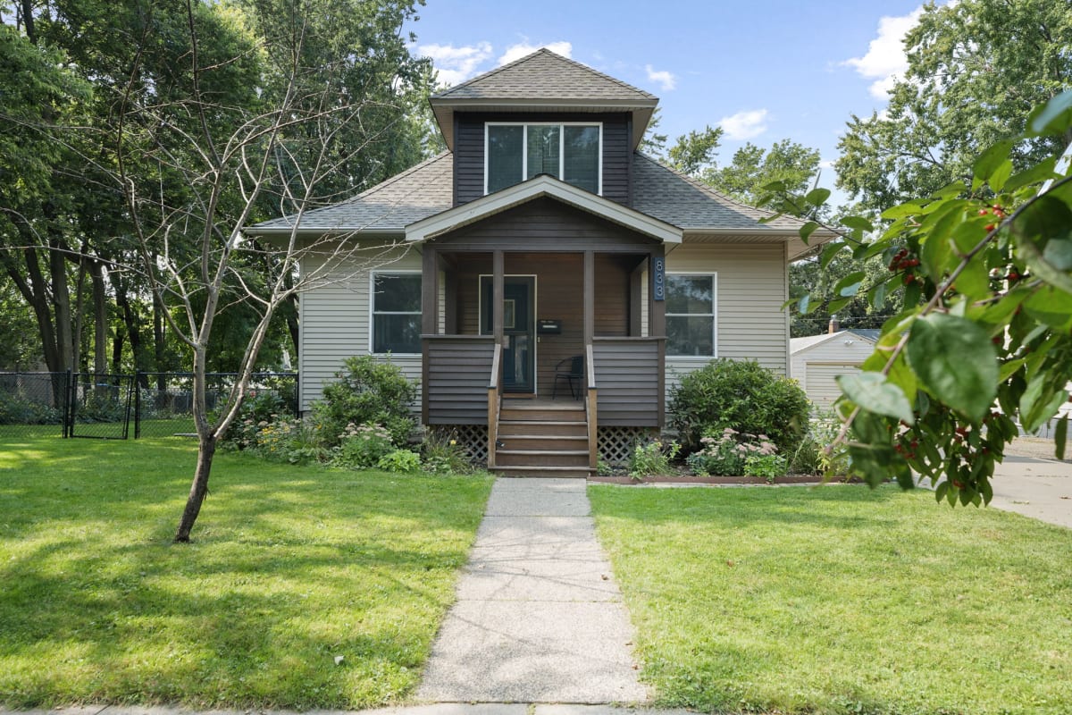 A charming two-story house with inviting porch and lush greenery.
