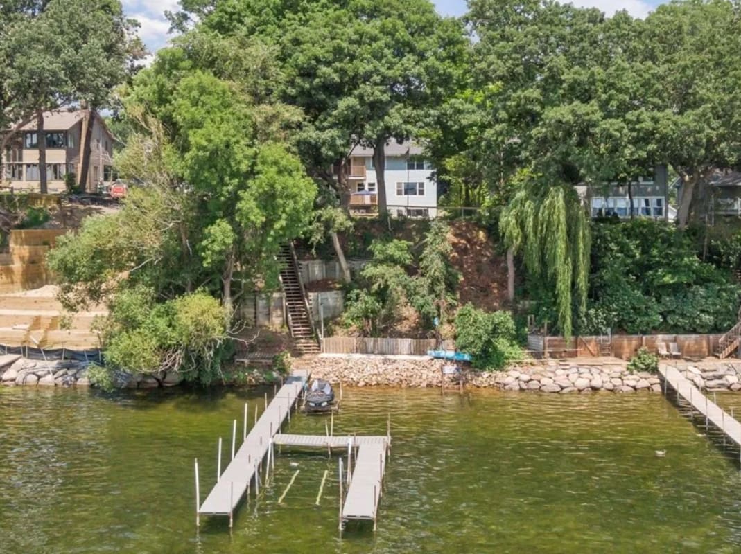 A serene lakeside view with a wooden dock and lush greenery.