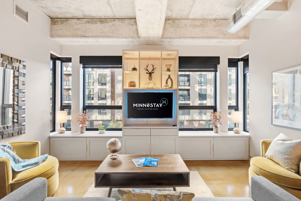 A modern living room with large windows, stylish furnishings, and a focus on comfort.