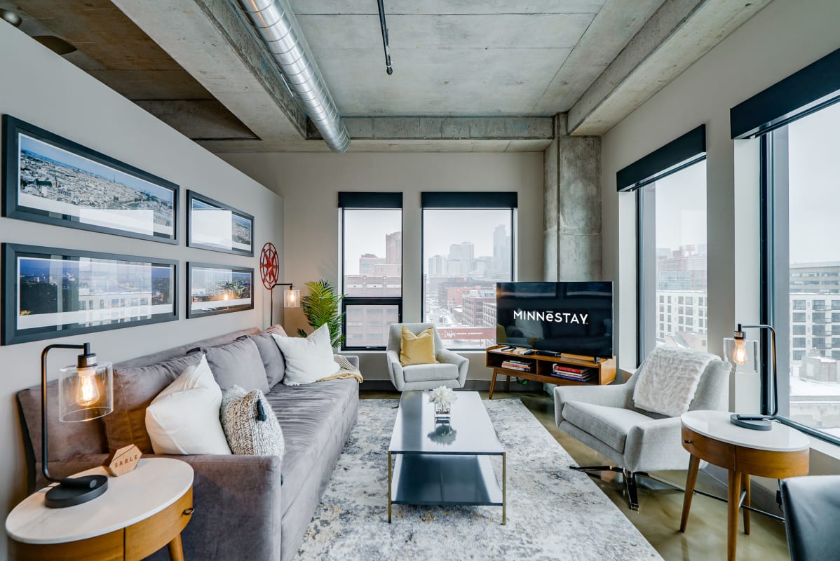 Modern living room with a city view, featuring an industrial design and cozy decor.