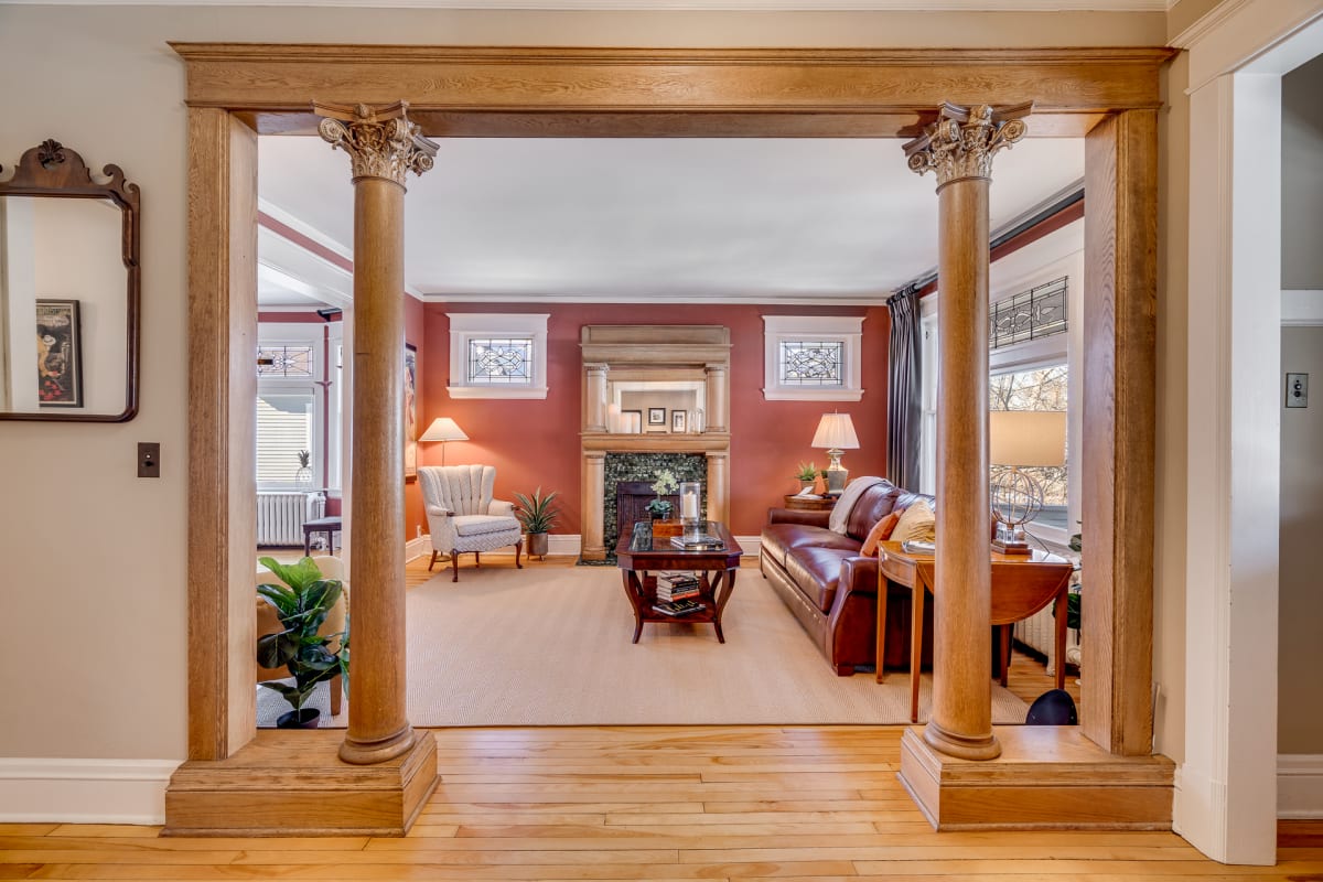 A cozy living room framed by ornate columns featuring warm tones and elegant furnishings.