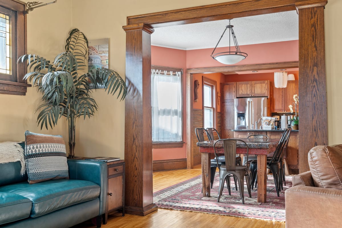 A warm and inviting living-dining area featuring a teal couch and rustic dining table.