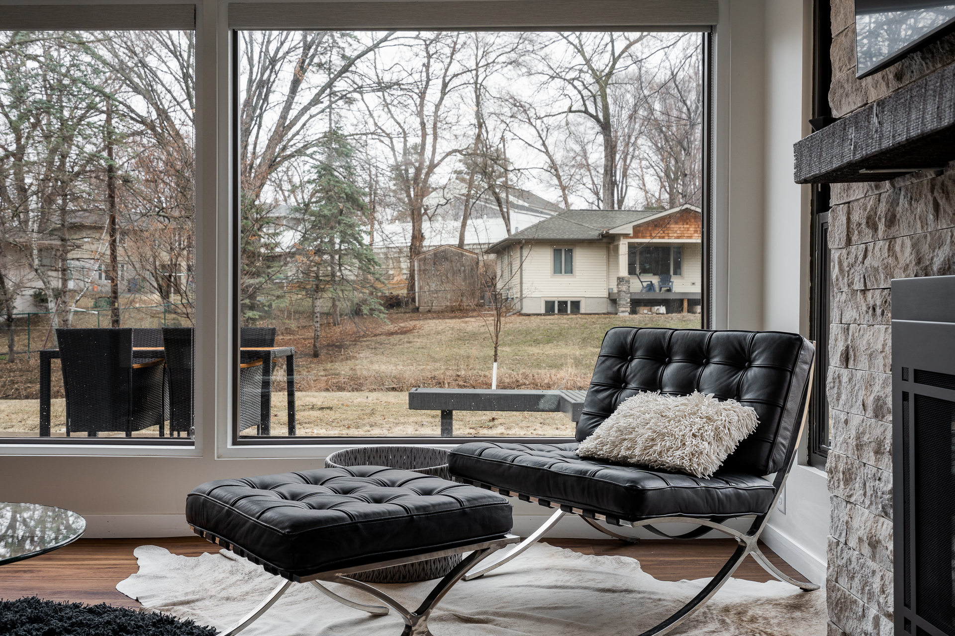 A stylish interior featuring a black leather chair and a view of a serene backyard.