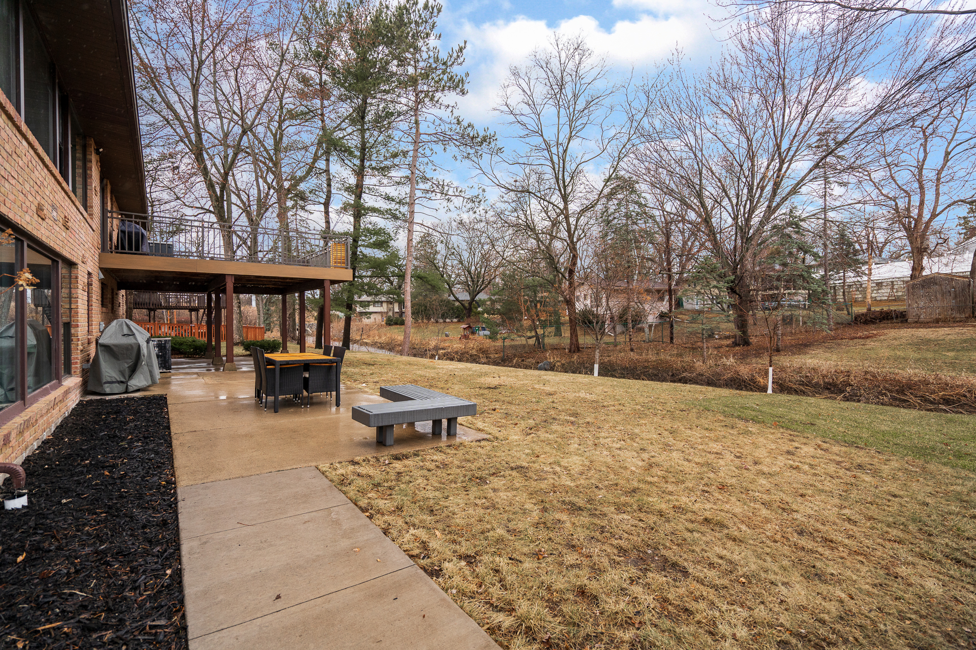 A serene backyard view of a modern home featuring a dining area and lush greenery.