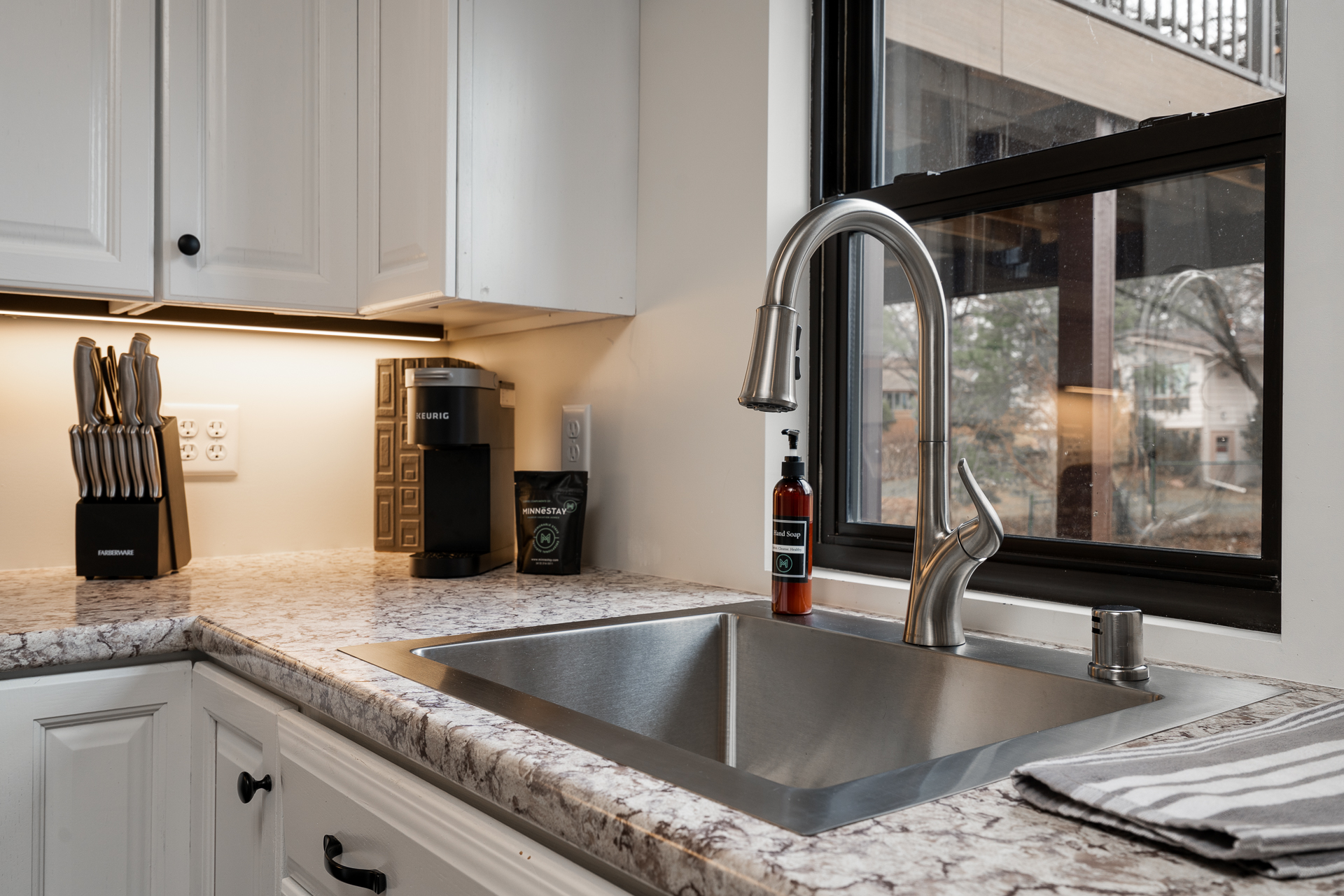 A modern kitchen with a stylish sink, coffee maker, and knife set.