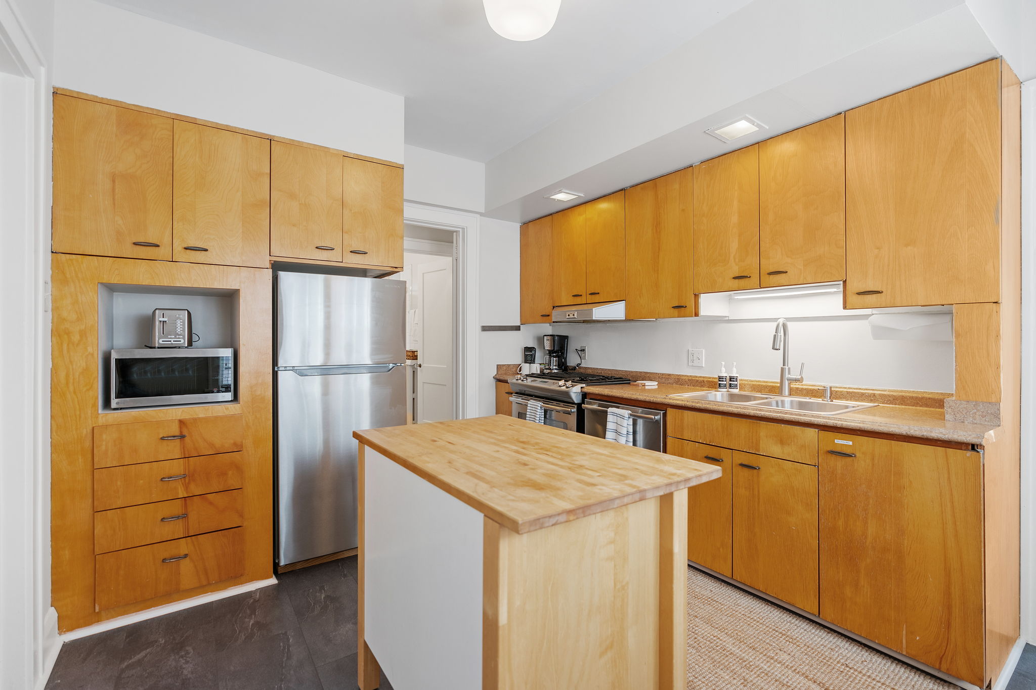 A modern kitchen with light wood cabinetry and stainless steel appliances.