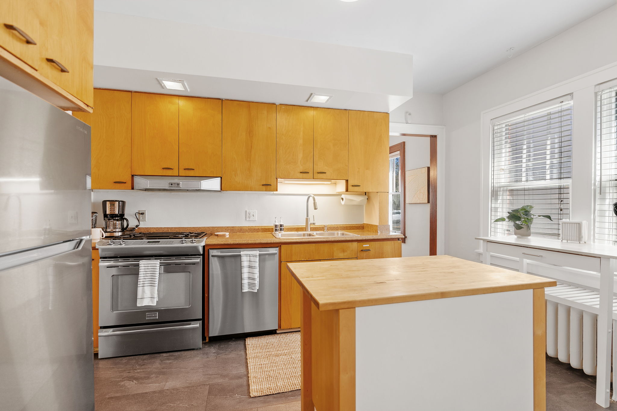 A modern kitchen with warm wooden cabinets and stainless steel appliances.