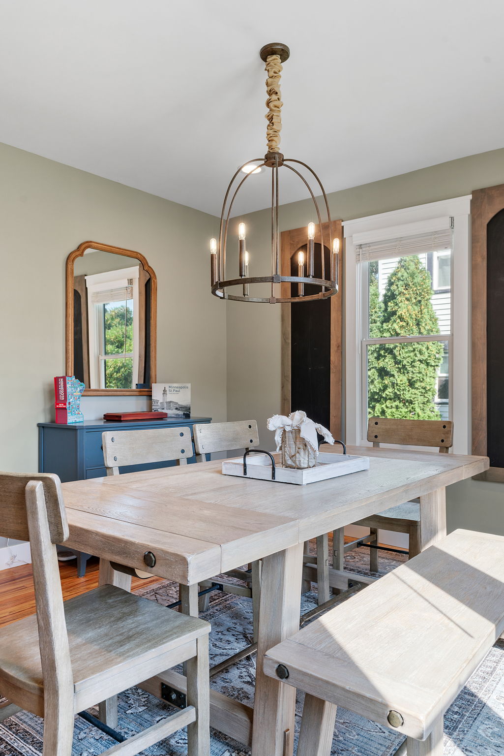 A cozy dining room featuring a wooden table, chairs, chandelier, and decor.