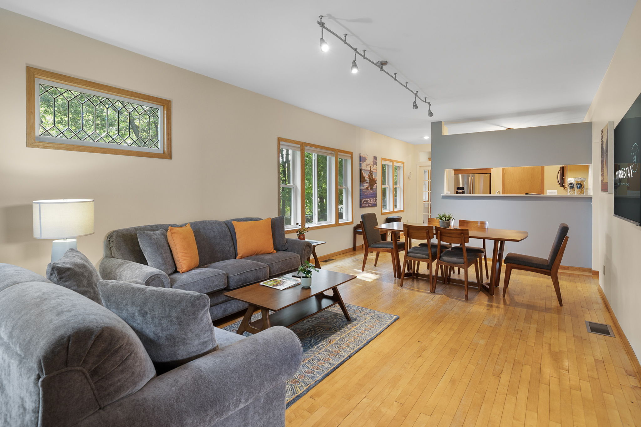 Modern living area with a grey sofa, orange cushions, and a dining table.