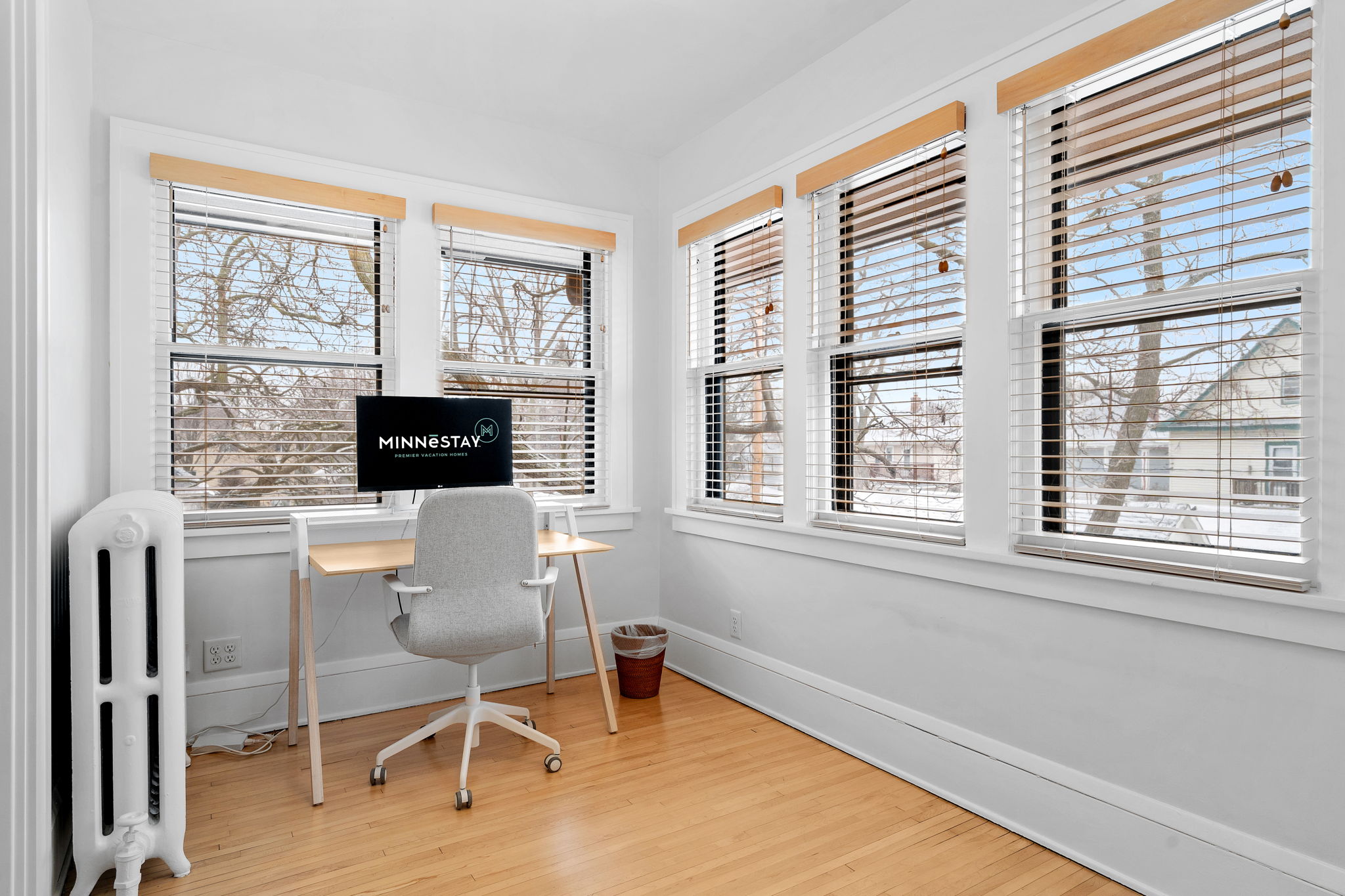 A bright and inviting home office with a stylish desk and views of winter trees.