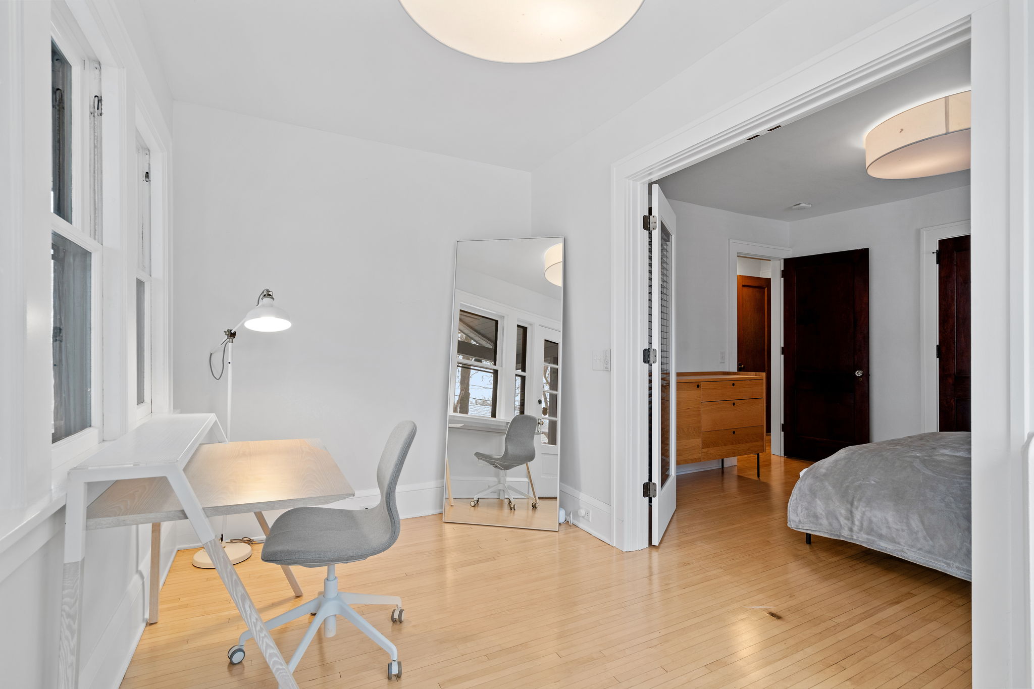 A modern workspace and cozy bedroom area in a bright, minimalist design.