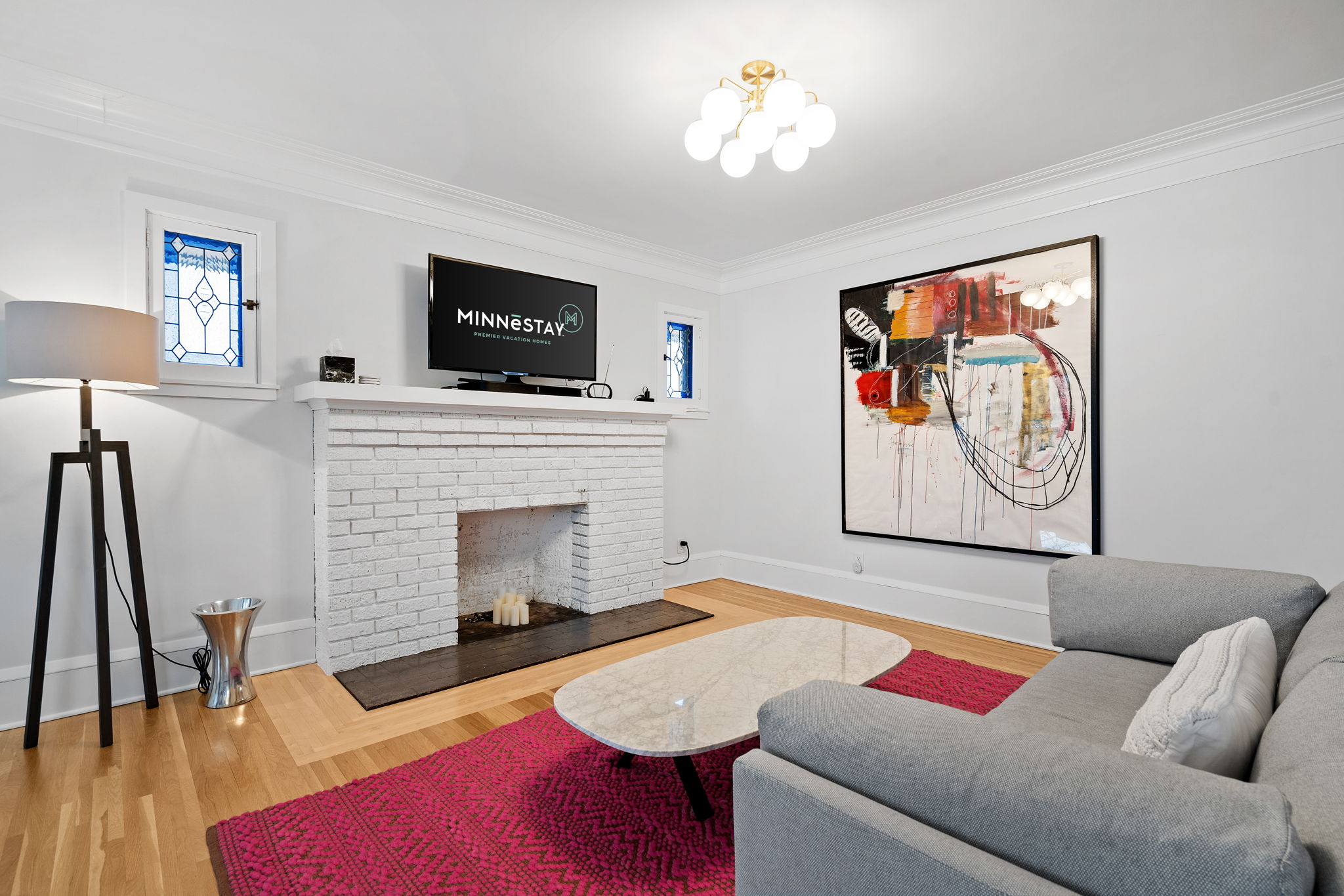 A modern living room featuring a gray couch, marble coffee table, and colorful artwork.