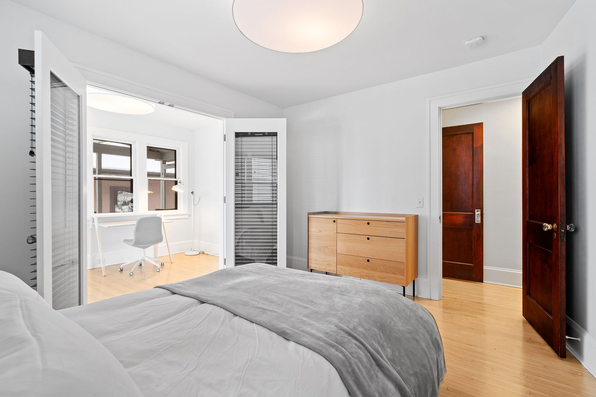 A modern bedroom featuring minimalist design elements and a cozy workspace.
