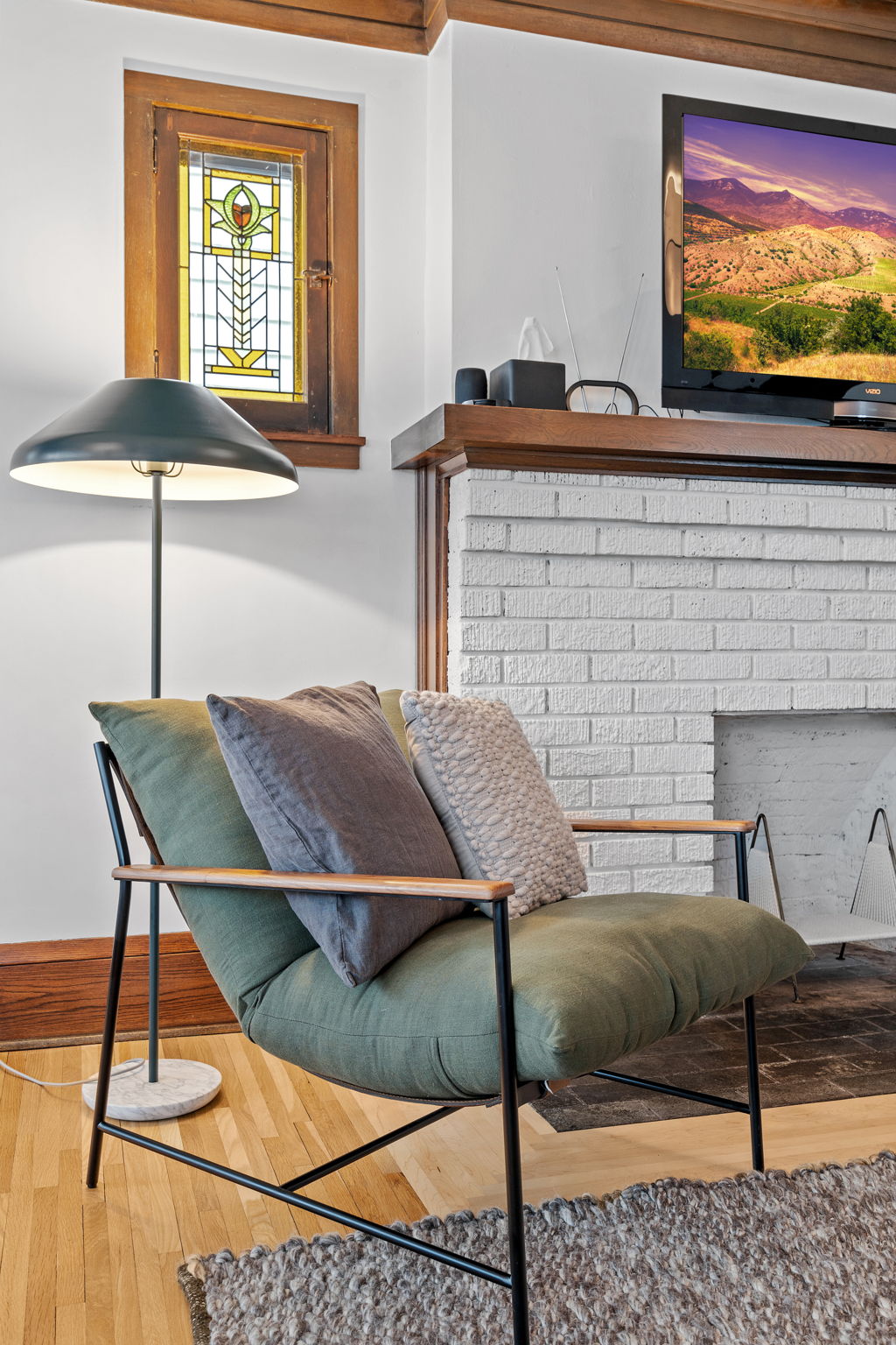 A cozy living room featuring a stylish armchair and stained glass window.