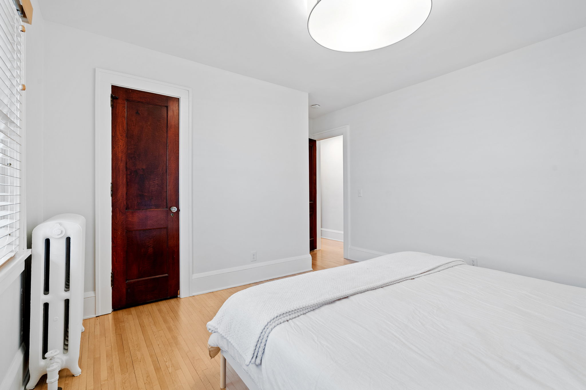 A minimalistic bedroom featuring a wooden door and vintage radiator.