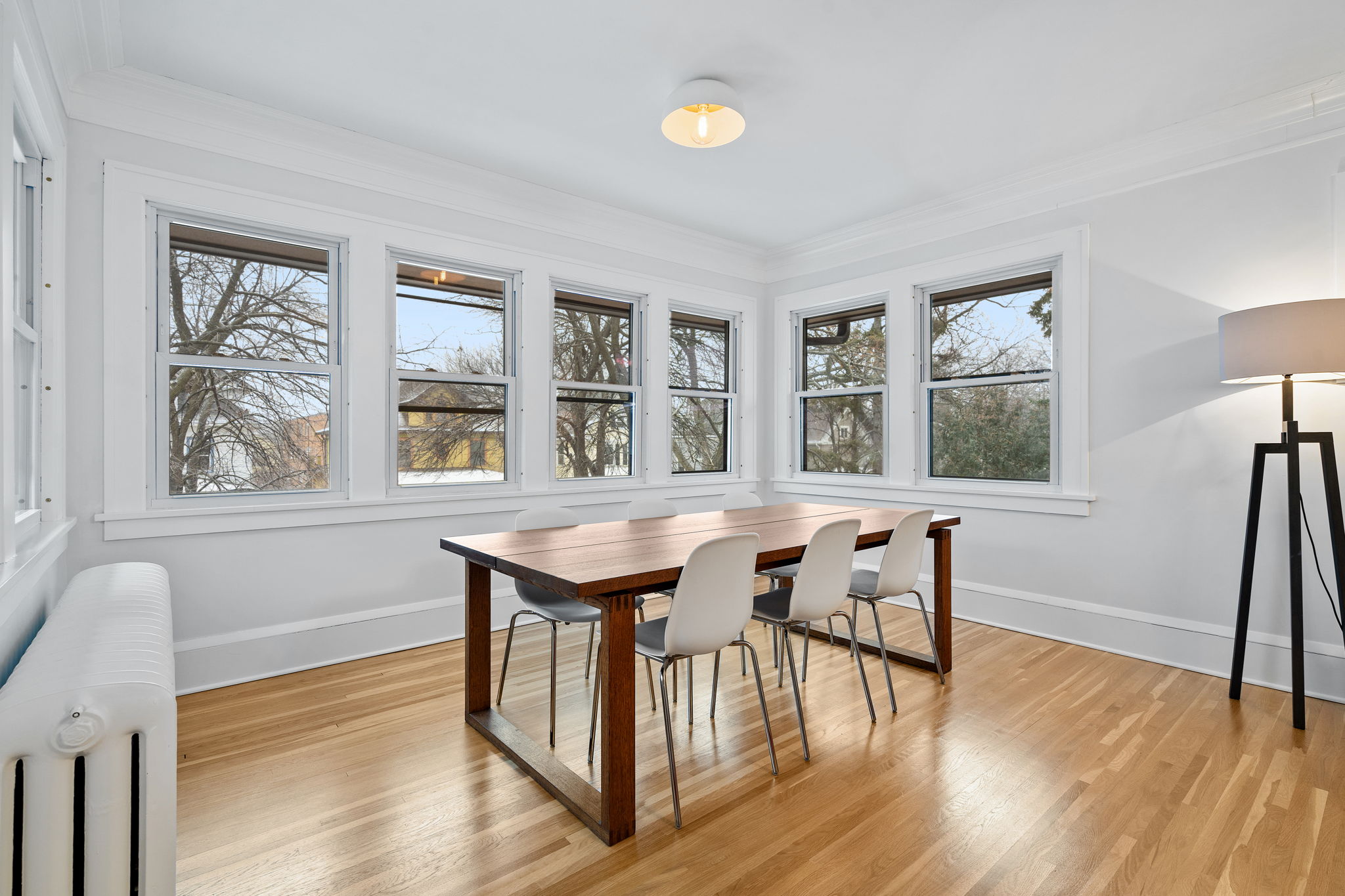 A bright and modern dining room with a wooden table and contemporary chairs.