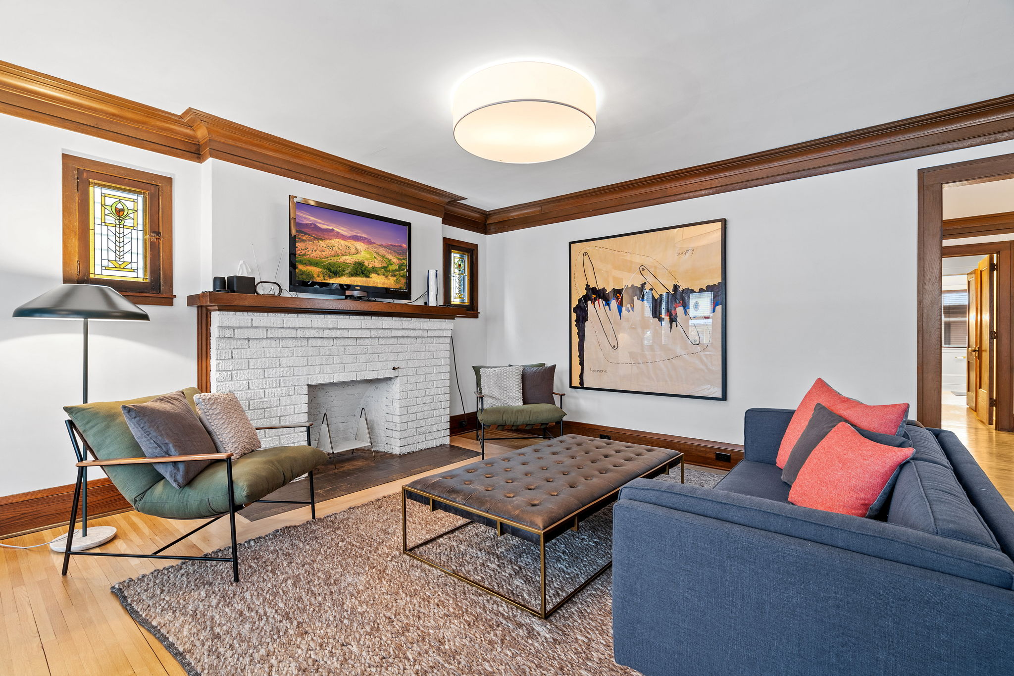 A modern living room with stylish decor, featuring a blue sofa, abstract art, and a warm ambiance.