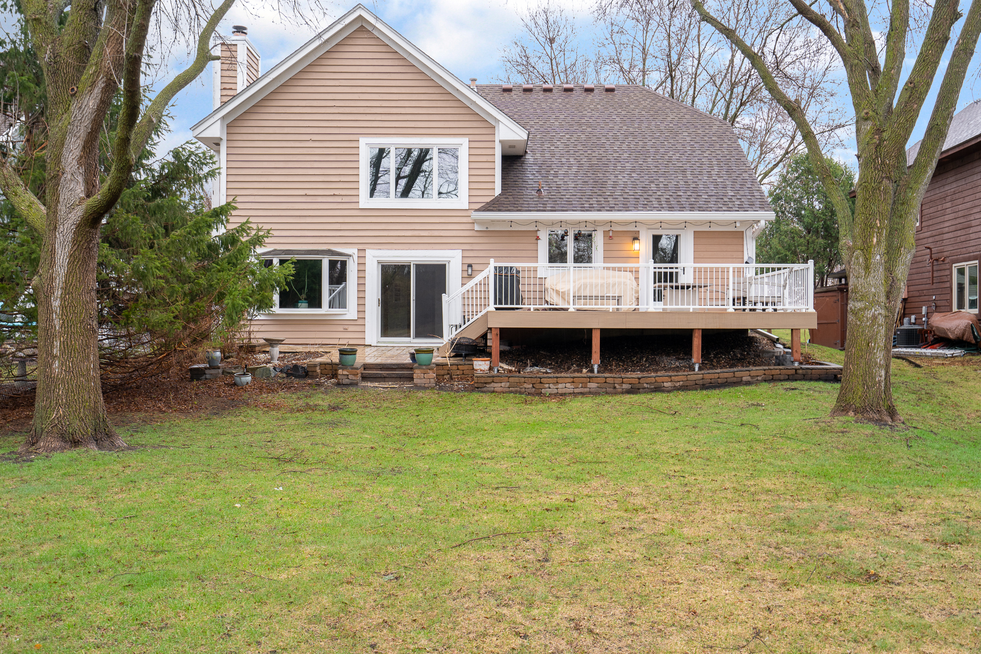 A cozy two-story home with a welcoming wooden deck and lush backyard.